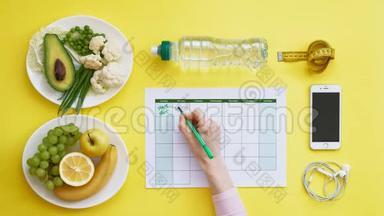 保持一个健身日历。健康食品的概念，饮食，俯视，黄色背景